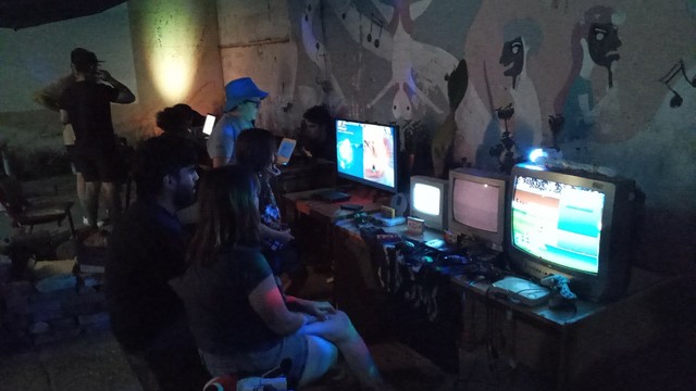 Gente jugando consolas clásicas de videojuegos.