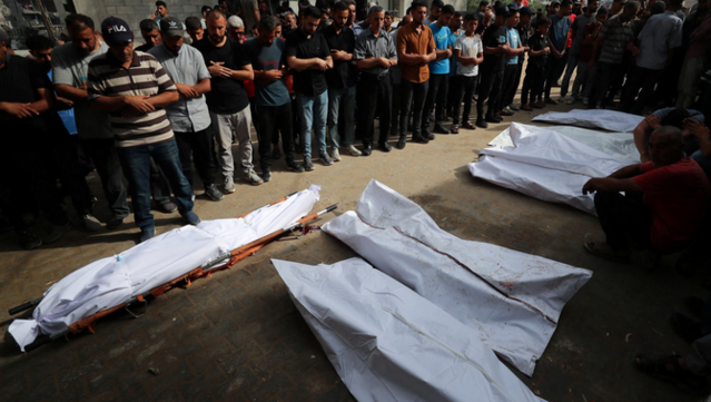 Ciutadans palestins resen davant diversos cossos a l'entrada de l'Hospital Al-Shifa de Gaza (Reuters/Mahmoud Issa)