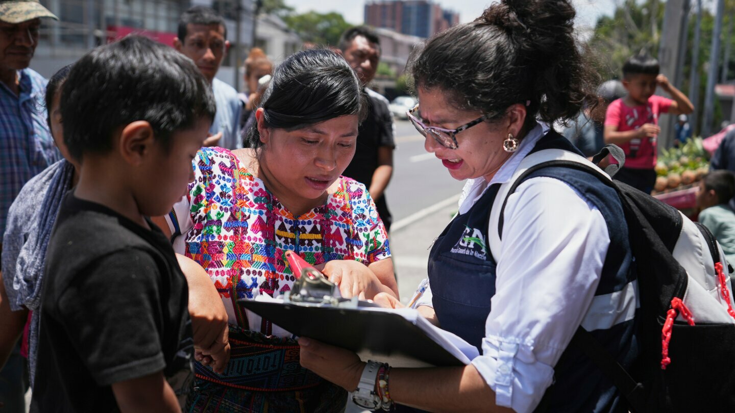 A relative of an unaccompanied minor deported from the United States reviews the list of those deported outside La Aurora International Airport, in Guatemala City, Aug. 31, 2025. (AP Photo/Moises Castillo, File)